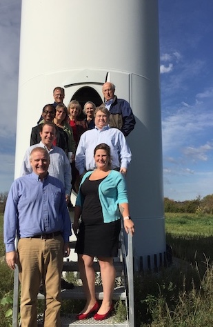 Ten staff and faculty members pose in front of a wind turbine on the Morris campus