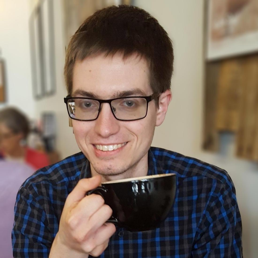 Adam Sychla holds a cup of (presumably) coffee
