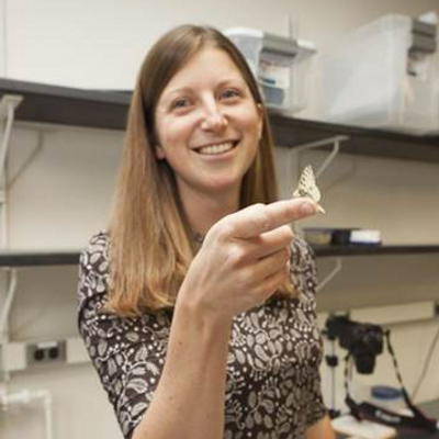 Professor Emilie Snell-Rood poses with a butterfly resting on her outstretched finger
