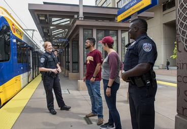 Two UMPD officers have a friendly conversation with students on the light rail platform